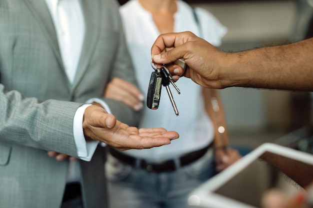 Plan rapproché du mécanicien donnant des clés de voiture à son client dans un atelier