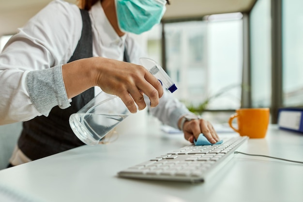 Plan rapproché de femme d'affaires nettoyant son clavier d'ordinateur dans le bureau