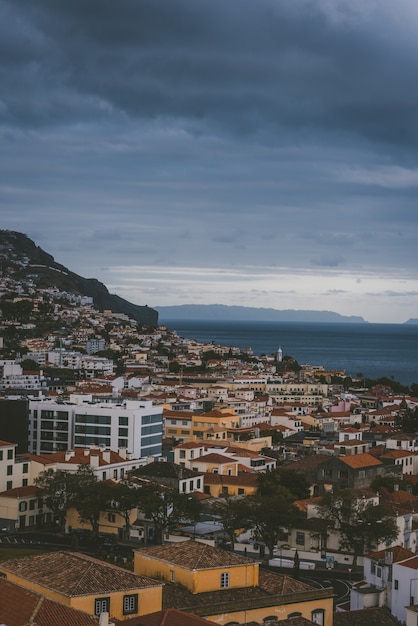 Plan vertical de bâtiments sur la montagne sous un ciel nuageux à Funchal, Madeira, Portugal.