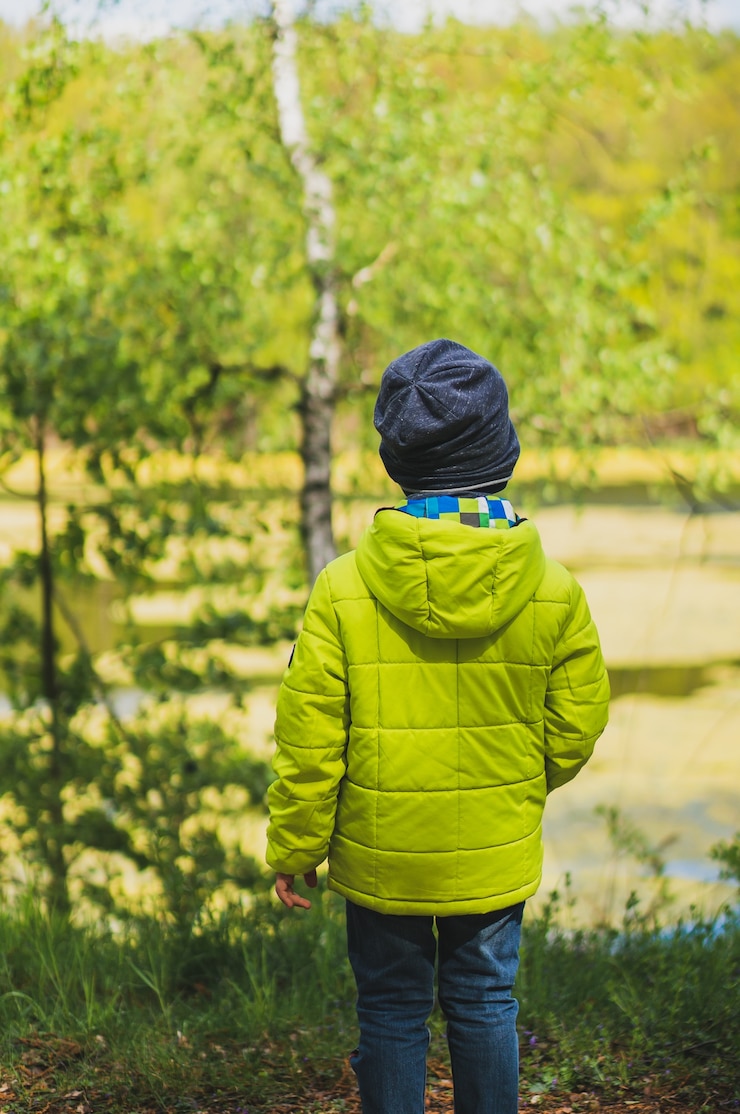 Photo gratuit plan vertical d'un enfant avec un manteau jaune jouant dans l'aire de jeux