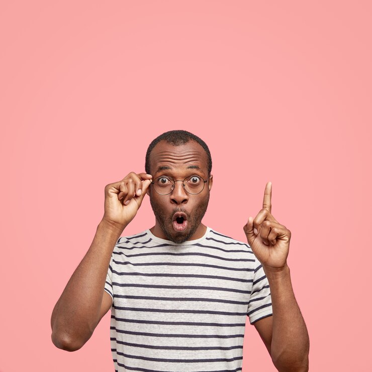 Photo gratuit plan vertical d'un homme afro-américain stupéfait émotive indique avec l'index au-dessus