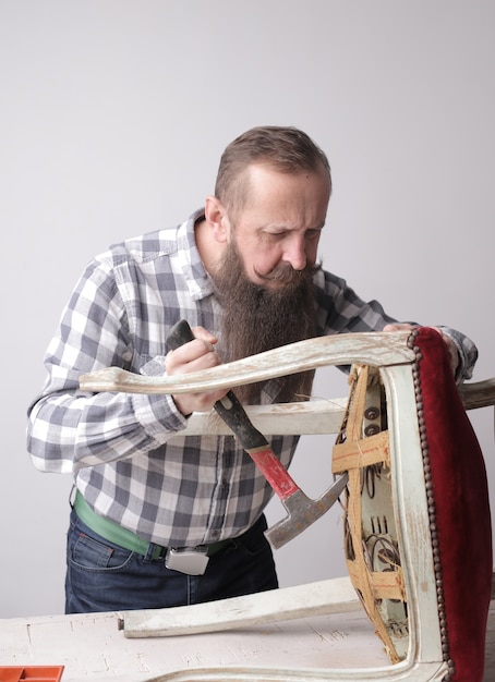 Photo gratuite plan vertical d'un homme avec une longue barbe et une moustache fixant une chaise cassée