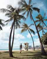 Photo gratuite plan vertical d'un homme marchant sur la plage couverte de palmiers tout en profitant de la journée ensoleillée