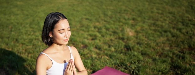 Photo gratuite plan vertical d'une jeune femme asiatique faisant du yoga pratique de la pleine conscience souriant et semblant détendu