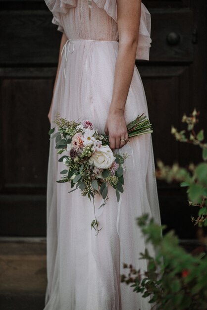 Plan vertical d'une mariée portant une robe de mariée tenant un bouquet de fleurs