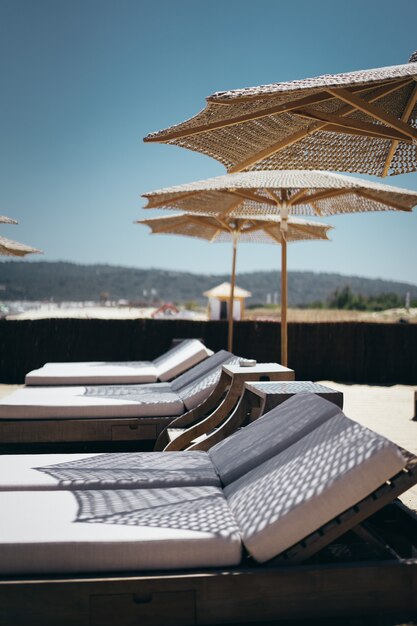 Plan vertical sélectif de chaises longues blanches sous les parasols de la plage