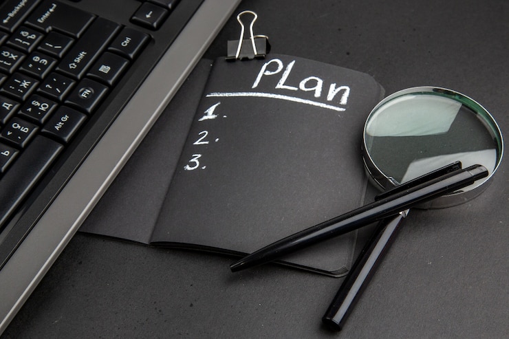 Photo gratuit plan de vue de dessous écrit sur le bloc-notes noir lupa stylo clip de reliure sur fond noir
