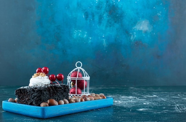 Une planche bleue avec un morceau de gâteau au chocolat et des noix de macadamia. photo de haute qualité