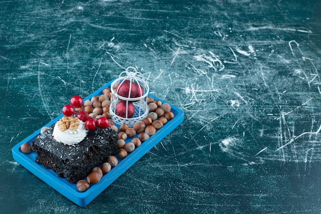 Une planche bleue avec un morceau de gâteau au chocolat et des noix de macadamia. photo de haute qualité