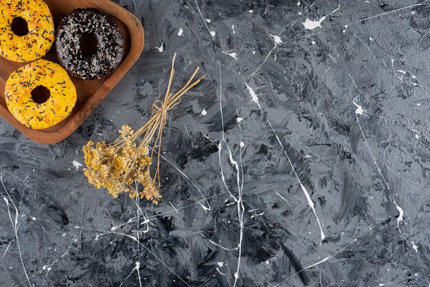 Planche de bois de beignets glacés doux sur une surface en marbre.