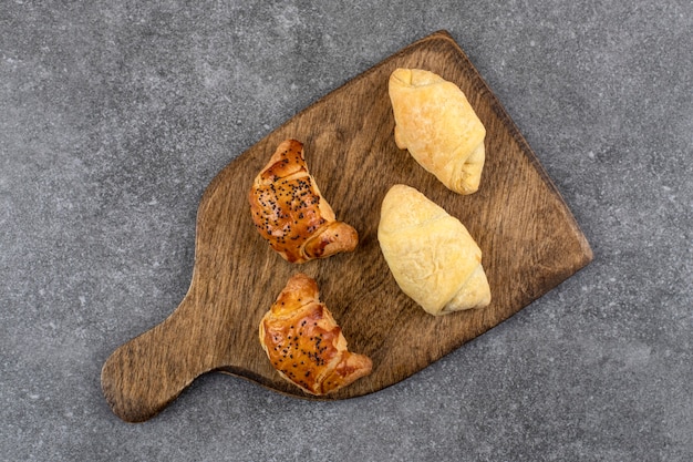 Planche de bois de biscuits frais mixtes sur table en pierre.