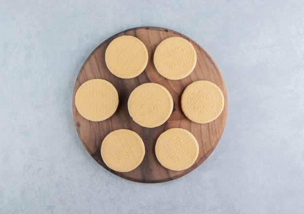Une planche en bois avec des biscuits ronds sucrés.
