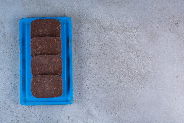 Une planche en bois bleue de biscuits au chocolat sur fond gris