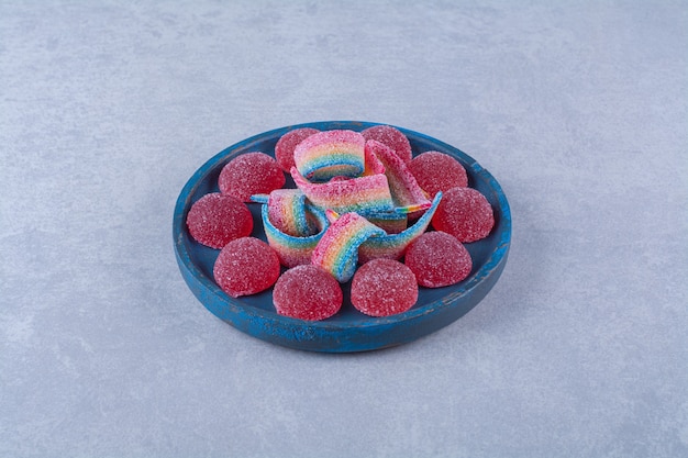 Une planche en bois bleue de bonbons gélifiés rouges sucrés avec de la réglisse arc-en-ciel sucrée. photo de haute qualité