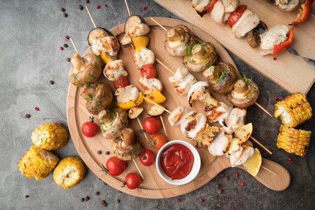 Planche de bois avec brochettes de poulet et légumes grillés sur table