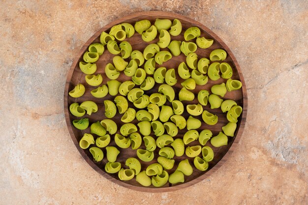 Une planche de bois avec des macaronis verts non préparés