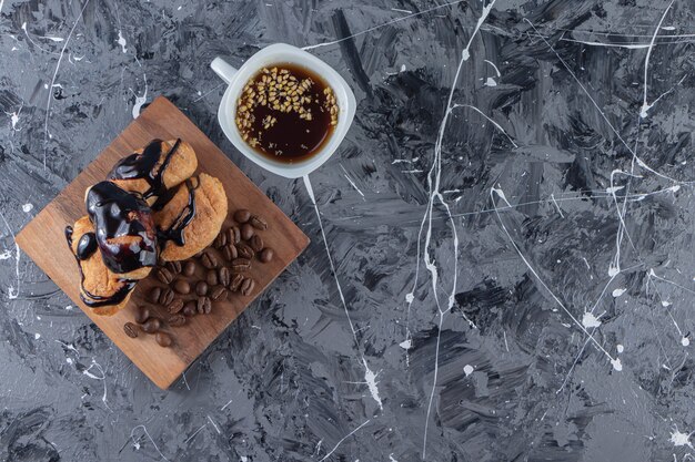 Une planche en bois de mini croissants avec du chocolat et des grains de café.