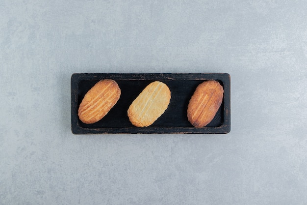 Une planche de bois noire pleine de biscuits sucrés.