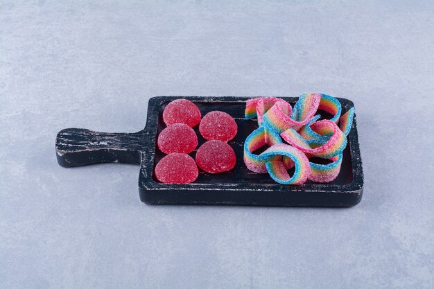 Une planche en bois noire pleine de bonbons colorés sucrés.