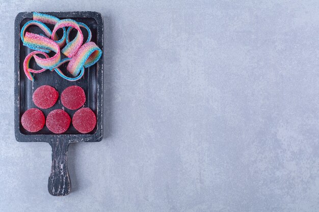 Une planche en bois noire pleine de bonbons colorés sucrés.