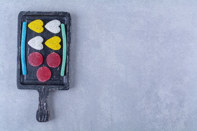 Une planche en bois noire pleine de bonbons colorés sucrés