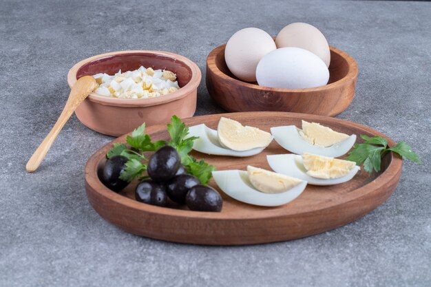 Une planche de bois avec des olives et des œufs durs. Photo de haute qualité