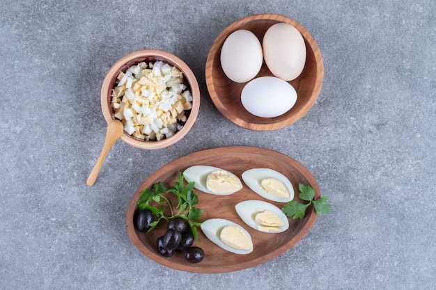 Une planche de bois avec des olives et des œufs durs. Photo de haute qualité