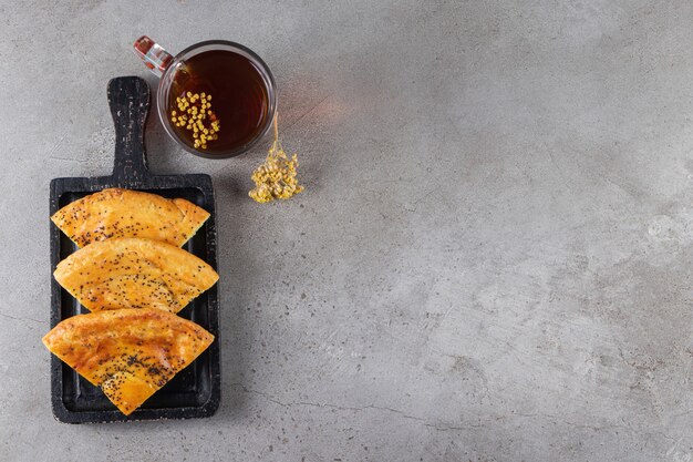 Planche de bois de pâtisseries fraîches tranchées et verre de thé sur une surface en marbre