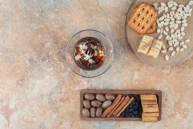 Une planche de bois pleine de biscuits sucrés et une tasse de tisane