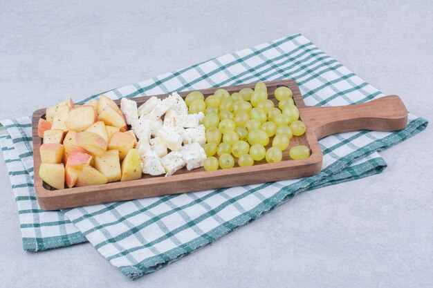 Une planche en bois pleine de fromage blanc et de fruits tranchés. photo de haute qualité