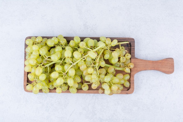 Une planche de bois pleine de raisins doux sur blanc