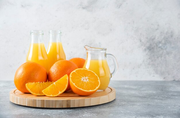 Une planche de bois pleine de tranches juteuses de fruits orange sur table en pierre.