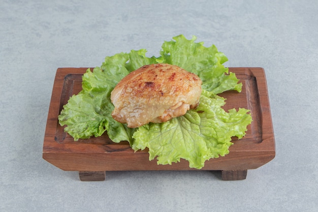 Une planche de bois de poulet frit avec de la laitue .