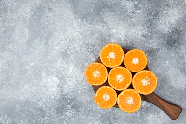 Photo gratuite une planche en bois de tranches juteuses de fruits orange sur table en pierre.