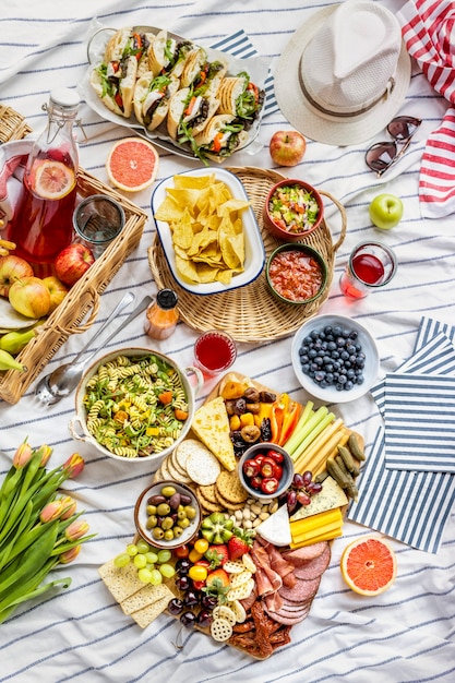 Planche de charcuterie avec de la charcuterie, des fruits frais et du fromage sur une nappe de pique-nique