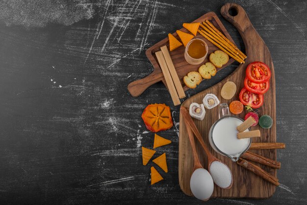 Planche à collation avec frites, craquelins et pâtisseries sur le plateau en bois au centre