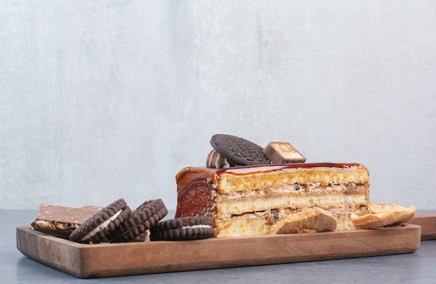 Une planche à découper en bois de biscuits et morceau de gâteau.