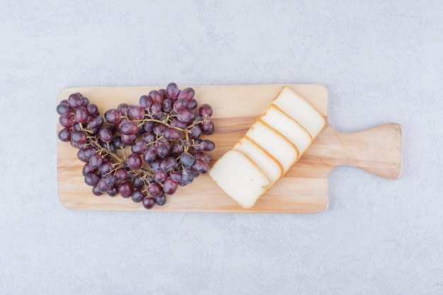 Une planche à découper en bois avec du pain tranché et des raisins. photo de haute qualité