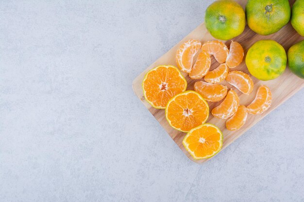 Planche à découper en bois pleine de mandarines aigres sur fond blanc. photo de haute qualité