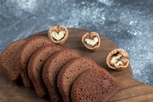 Photo gratuite une planche à découper en bois avec des tranches de pain et des noix.