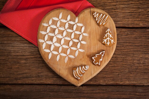 planche à découper en forme de coeur avec des biscuits sur une serviette rouge