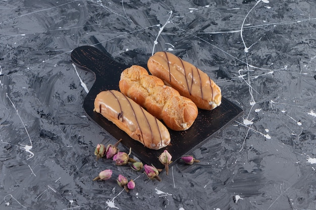 Photo gratuite planche à découper noire de délicieux éclairs sur table en marbre.