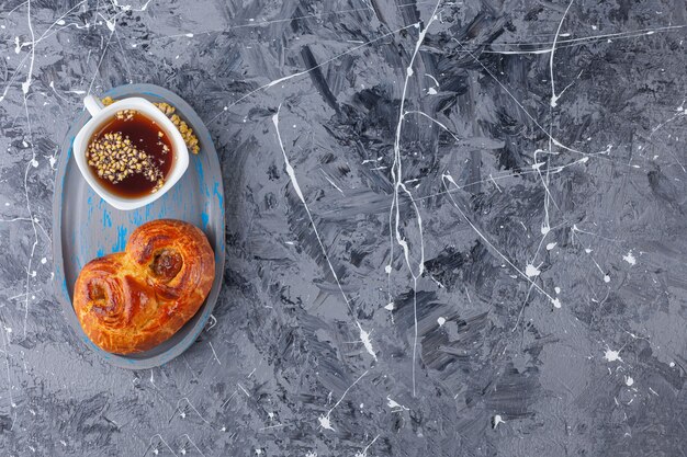 Une planche de pâtisserie douce torsadée et une tasse de thé sur un fond de marbre.