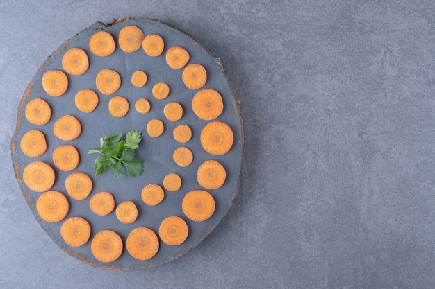 Planche de persil et de carottes tranchées, sur la surface en marbre.