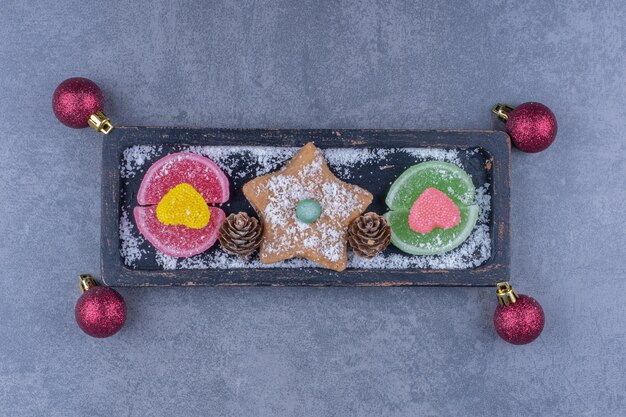 Photo gratuite une planche sombre avec des biscuits étoiles et des bonbons à la gelée sucrée