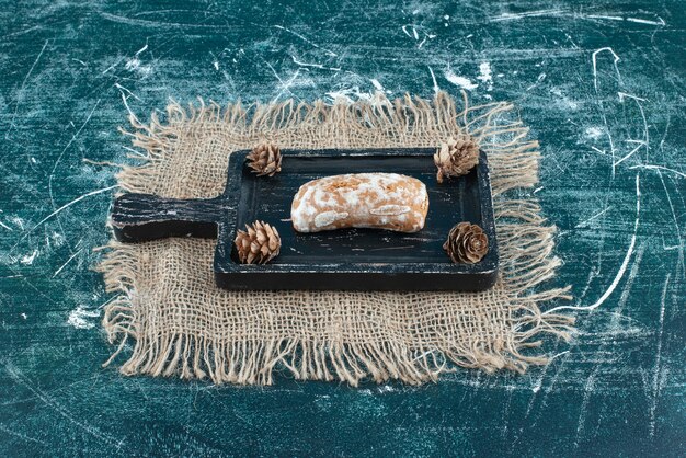 Une planche sombre avec du pain d'épice savoureux et des pommes de pin. photo de haute qualité