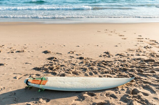 Planche de surf blanche allongée sur le sable