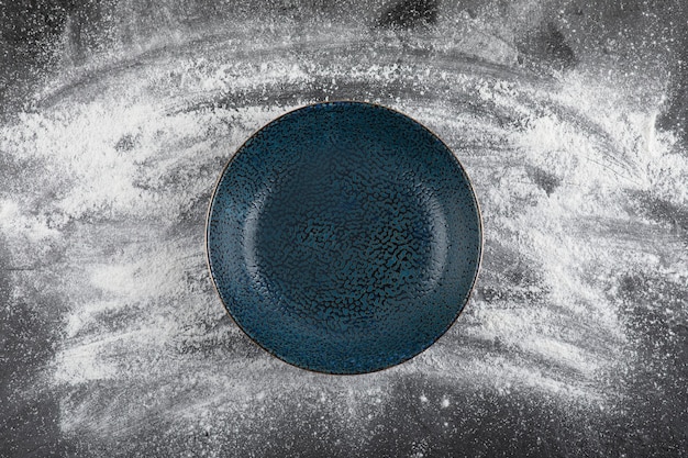 Plancher de blé renversé sur une surface noire et un bol noir vide