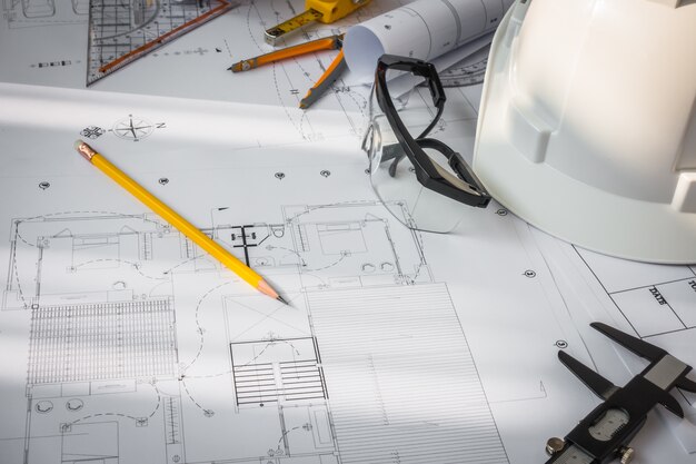 Les plans de construction avec un casque blanc et des outils de dessin sur bluepr