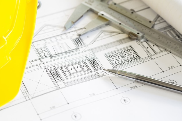 Les plans de construction avec casque jaune et des outils de dessin sur bluep